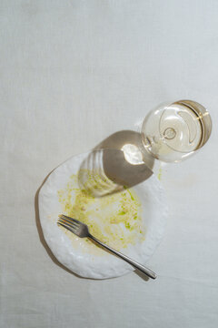 Empty Plate with Fork and Wine Glass on White Tablecloth