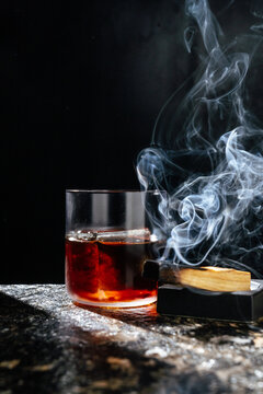 Smoky whiskey cocktail with burning wood garnish