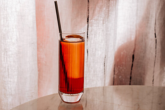 Iced cocktail in tall glass with straw