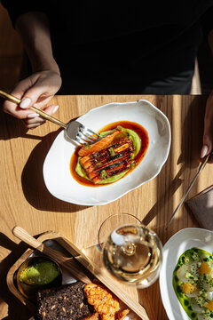 Person eating gourmet salmon dish with wine and appetizers
