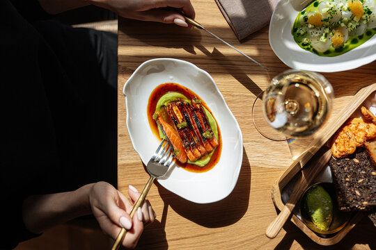 Woman dining on seared salmon with avocado puree and wine