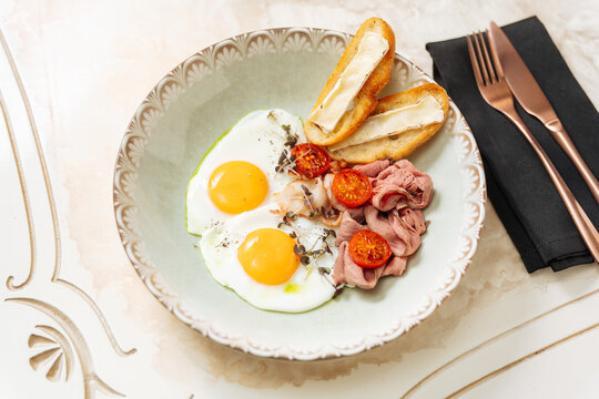 Breakfast plate with eggs, meat, tomatoes, and bread
