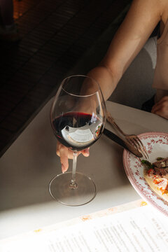 Woman Holding Glass of Red Wine at Restaurant Table