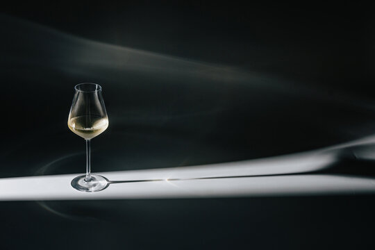 Glass of white wine with dramatic lighting and long shadow