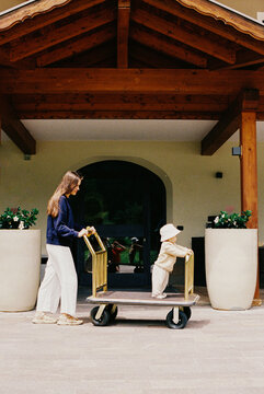 Woman and Baby Playing with Luggage Cart Outside Film Photo 