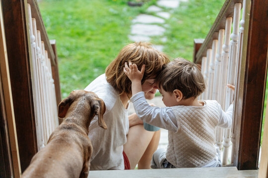 Mother and child bonding on porch with dog nearby