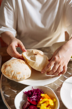 Person holding freshly baked pita bread with side of pickled vegetable