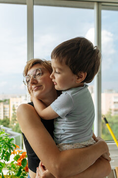 Mother hugging child by window indoors 