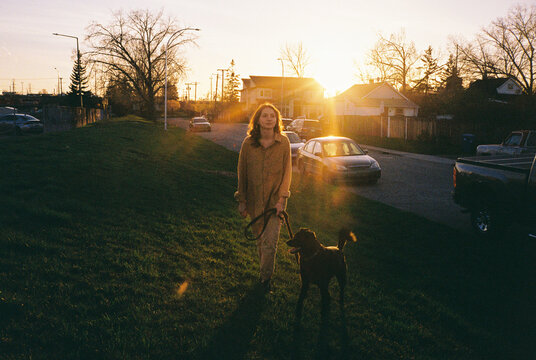 Woman walks her black dog in suburban setting 