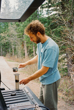 Man brewing coffee from pick up truck during road trip 