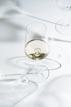White wine glass with empty glass on white surface