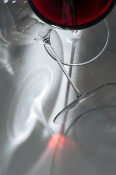 Title: Red wine glass casting reflections on surface - Descripti