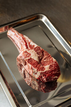 Raw tomahawk steak on metal tray