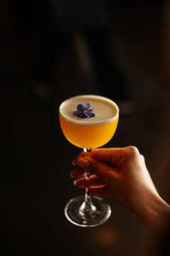 Hand Holding Yellow Cocktail with Flower
