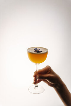 Yellow Cocktail with Purple Flower Garnish
