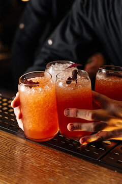 Hand Holding Glasses of Orange Cocktails
