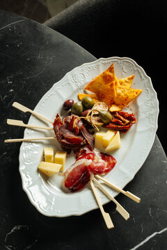 Charcuterie platter with cheese, cured meats, olives, and chips
