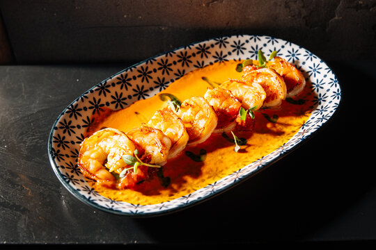 Delicious grilled shrimp garnished with herbs served on a decorative p
