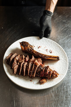 Sliced grilled tomahawk steak on white plate