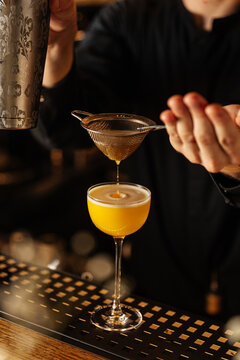Yellow Cocktail Being Strained into Glass