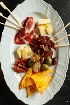 Charcuterie plate with cured meats, cheese, olives, and chips