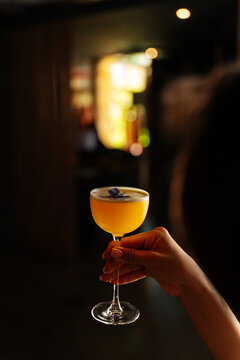 Womans Hand Holding Yellow Cocktail with Flower 