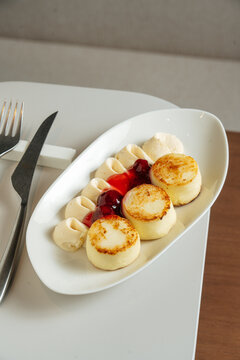 Cheese pancakes with cream and berry sauce on white plate