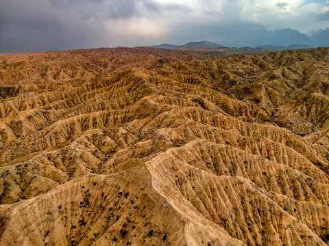 Aerial view of Kan'on Aksay featuring intricate eroded ridges and reddish-brown earth under a dramatic cloudy sky in Ak Say, Issyk-Kul Region, Kyrgyzstan.