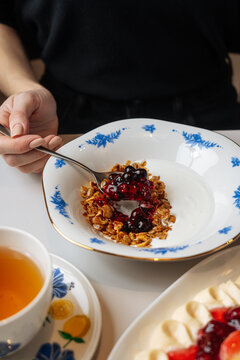 Woman eating granola with yogurt and berry jam