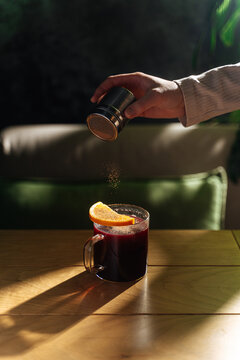 Hand sprinkling spice over mulled wine