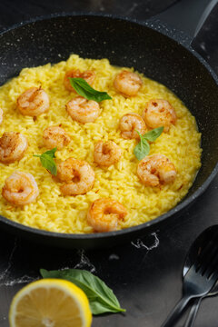  Creamy saffron risotto with shrimp and basil in a black frying pan