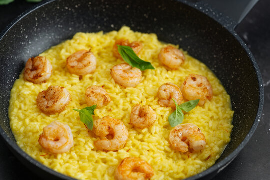 Creamy saffron risotto with grilled shrimp in black pan