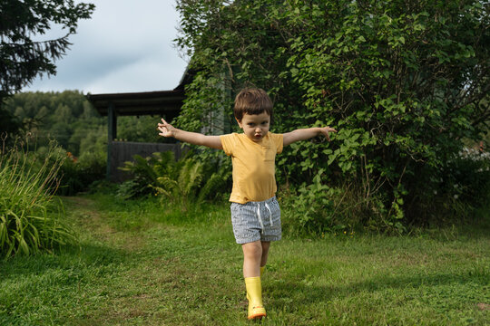 Child walking with outstretched arms on grassy path