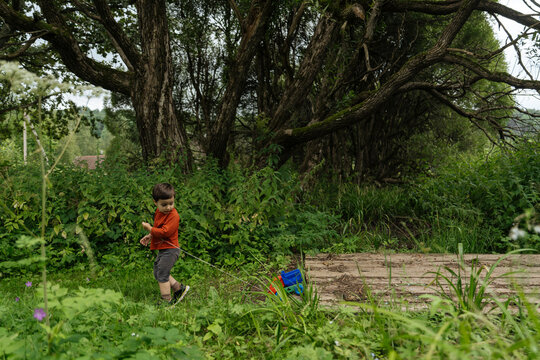 Child pulling toy truck through forest clearing