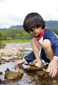 Chinese boy plays in a mountain stream.