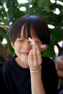 Closeup of a Chinese boy holding blooming flowers from the yard.