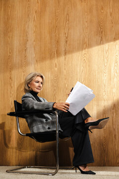 Woman sitting in chair reviewing printed documents