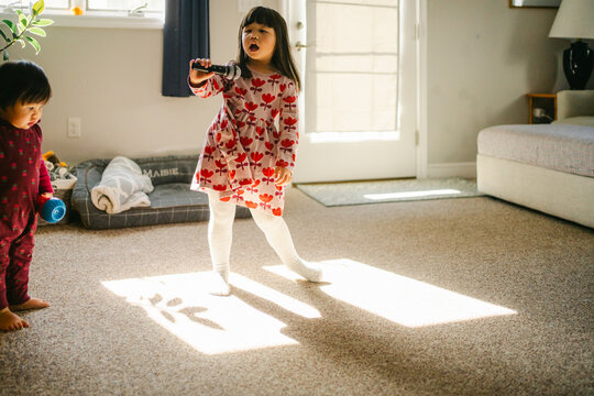 siblings dancing in living room in sunlight coming form window 
