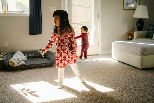 two little girls, sisters, singing and dancing in living room 