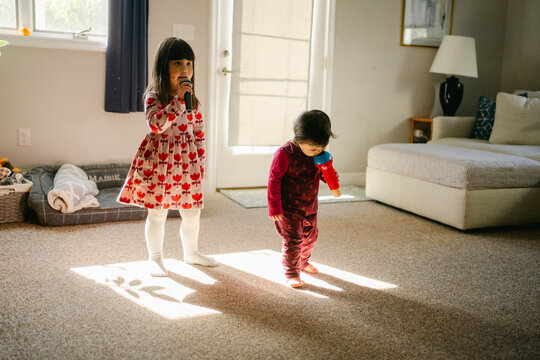 siblings dancing in living room in sunlight coming form window 