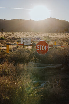 Road Closed Sign with Stop Barrier in Desert at Sunset