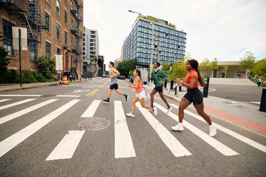 A bunch of athletes are jogging across the street