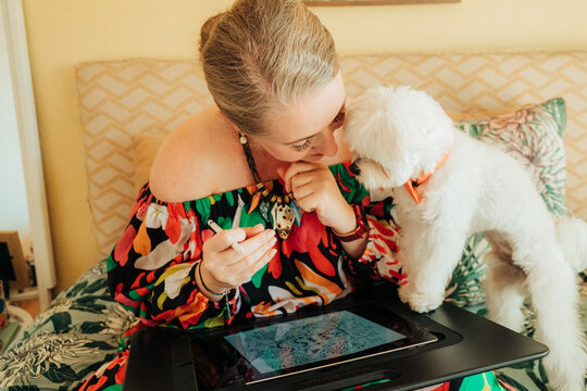 Woman and small dog sharing intimate moment during drawing sessi