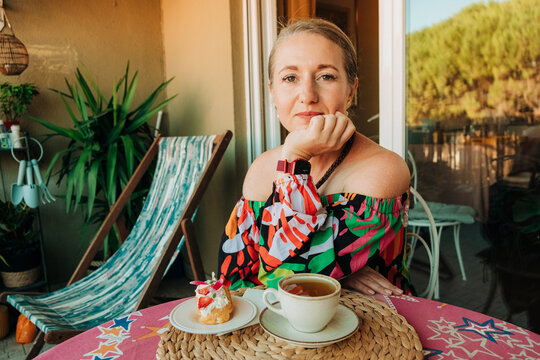 Woman sitting at balcony table with tea and sweets