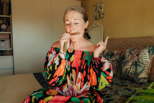 Woman playing jew's harp with closed eyes at home