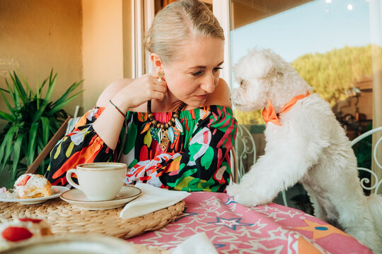 Woman leaning toward dog during relaxed tea time