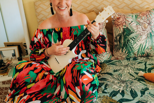 Woman playing ukulele at home