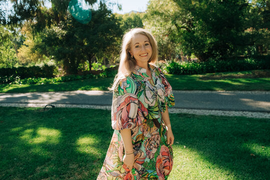 Elegant woman in colorful dress in sunlit park