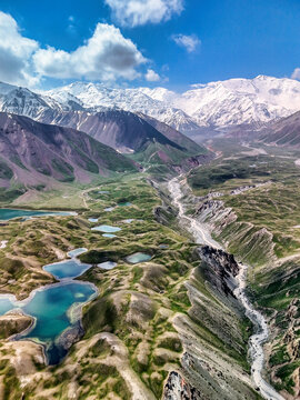 Aerial view of Tulpar Lake and surrounding alpine landscape with turquoise ponds, a winding river, and snow-capped peaks in Alay District, Osh Region, Kyrgyzstan.