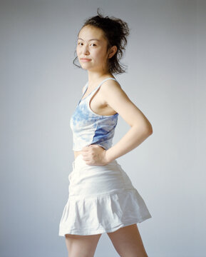 Confident Young Woman in Blue Tank and White Skirt
